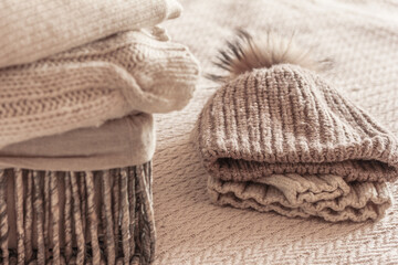 Fototapeta na wymiar Stack of cozy knitted wool clothes in wicker basket, sweater, jumpers, hat . Hygge mood, cold weather concept. Autumn or winter background.