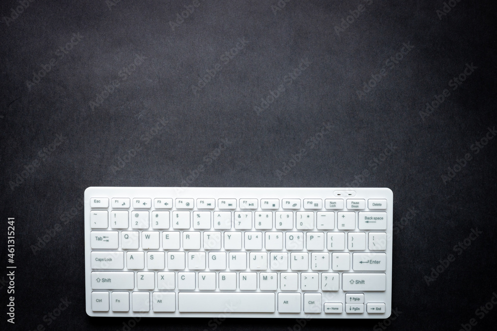 Fototapete white computer keyboard on a black background, free space for text or graphics