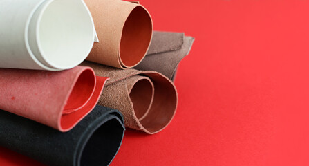 Pieces of leather material lie on a red background. Banner with place for text