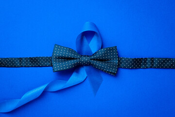 Cancer awareness blue. Blue ribbon, fashion bowtie isolated on deep blue background. Awareness prostate cancer of men health in November. November and International Mens Day.