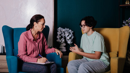 a psychologist and a teenage patient are sitting in a chair and having a conversation