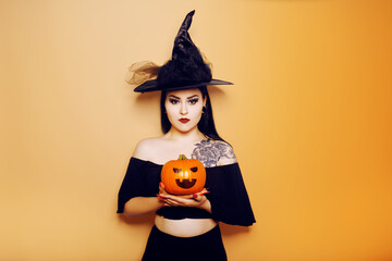 A witch girl holding a pumpkin in her hands, a woman celebrates Halloween, photo on a red background