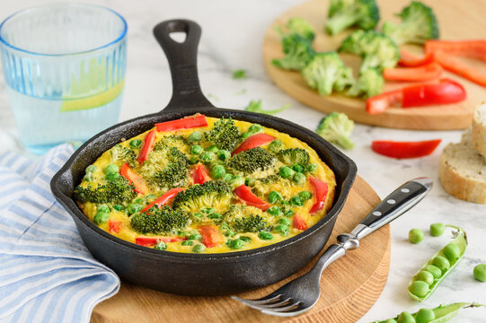 Omelet with vegetables: broccoli, pepper and green peas. Frittata in a frying pan. Selective focus
