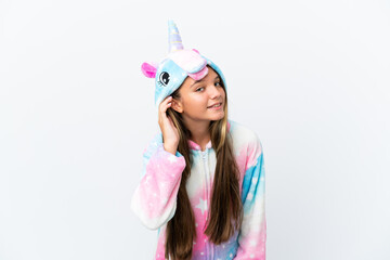 Little caucasian girl wearing unicorn pajama isolated on white background listening to something by putting hand on the ear