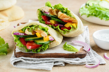 Pita with roasted chicken and vegetables: cucumber, tomato, pepper, red onion and yoghurt sauce. Healthy food. Selective focus 