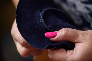 Woman's hands sewing leather blue craft shoes with needle. Shoemaker workshop artisan handmade...