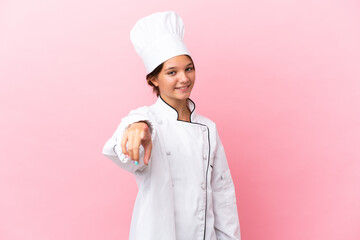 Little caucasian chef girl isolated on pink background points finger at you with a confident expression