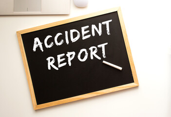 Text ACCIDENT REPORT written in chalk on a slate board. Office desk.