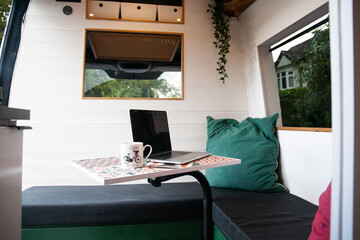 Campervan remote working setup with laptop on table in bright camper interior