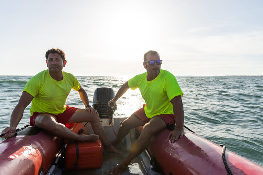 Male lifeguards riding inflatable motorboat