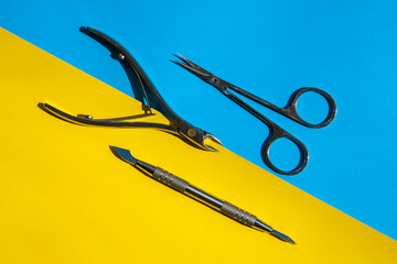 Set of disinfected manicure or pedicure tools on yellow and blue background Cuticle pushers and...