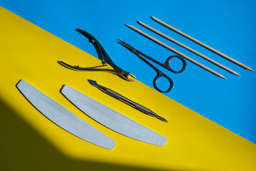 Set of disinfected manicure or pedicure tools on yellow and blue background Cuticle pushers and...