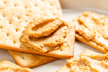 Peanut butter spread on soda crackers close up