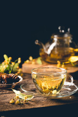 Cup of herbal tea with linden flowers on dark background