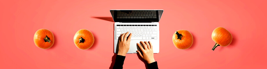 Autumn pumpkins with person using a laptop computer from above