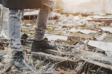 Unrecognizable young man stomping on rubble in ruins
