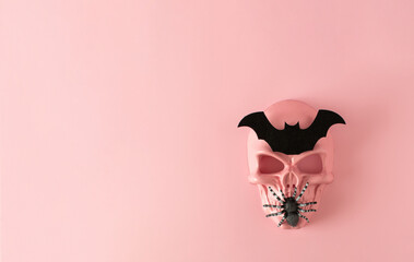 Creative minimalistic design made of pink skull mask with black spider and  bat. Minimal scary pink Halloween or day of the dead concept. Copy space. Top view.