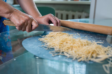 An unrecognizable woman cuts noodles. women's hands close-up