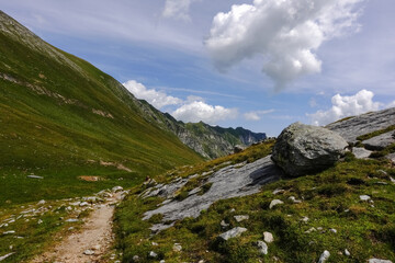 single round huge rock on a plattform near a hiking path in the mountains