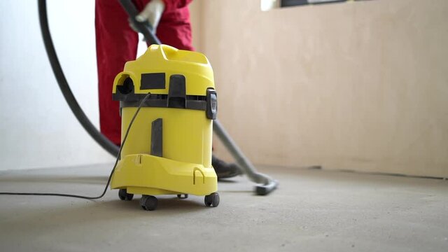 Dust removal with vacuum cleaner. A worker vacuums the floor with an industrial vacuum cleaner. Preparing the floor for tiling. Building cleaning service
