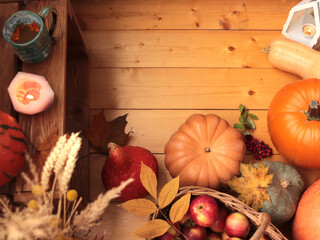 Autumn wooden background with pumpkins, cup of sea buckthorn tea, fall leaves, dried flowers and candles 