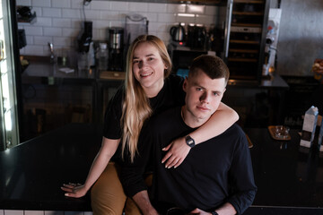 happy married couple in identical clothes family look - cafe owners or workers - in modern coffee shop. family business. loft cafe