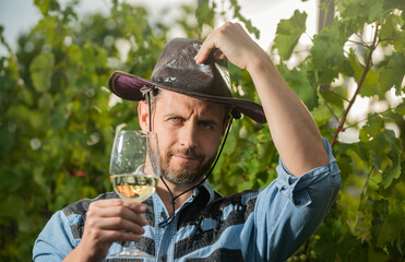 male vineyard owner. professional winegrower on grape farm. bearded man in hat with wine glass