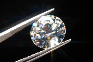 Diamond in tweezers selective focus, inspection and analyzing of brilliant cut crystal polish quality. Jewellery professional hand making in the studio. Macro shot, shallow depth of view.