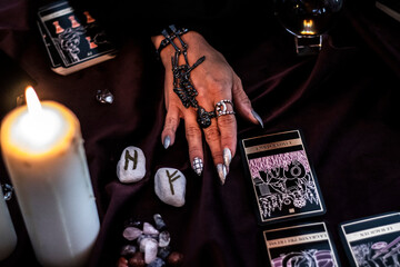 mysterious witch hand playing with runes and tarot card 
