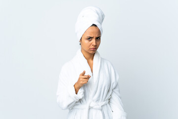 Young woman in bathrobe over isolated white background frustrated and pointing to the front