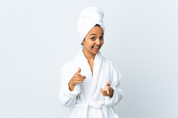 Young woman in bathrobe over isolated white background surprised and pointing front