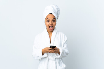 Young woman in bathrobe over isolated white background surprised and sending a message