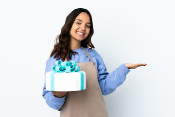 Pastry chef holding a big cake over isolated white background presenting an idea while looking smiling towards