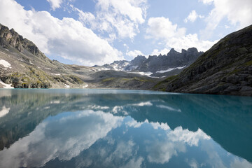 Obraz premium Amazing hiking day in one of the most beautiful area in Switzerland called Pizol in the canton of Saint Gallen. A wonderful view at the alpine lake called Wildsee with a tent by the lake. Epic view.