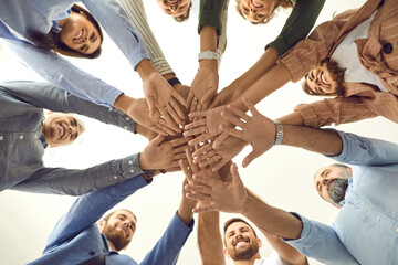Human support. Bottom view of a group of different people standing in a circle and folding their...