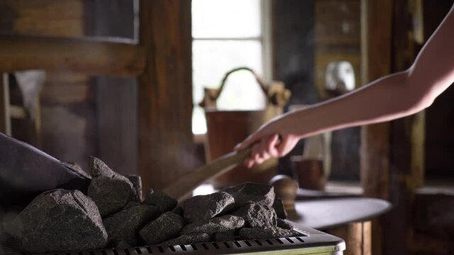 Interior of traditional Finnish sauna with wooden accessories and steam. Splashing water on hot stones.