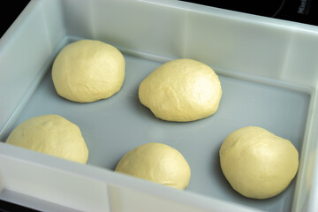 Pizza dough in a plastic tray.