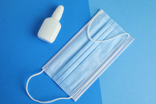 Nasal sprey and medical mask on blue background