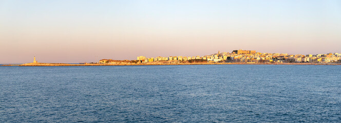 Town of Vieste and the lighthouse seen from the sea at sunset, Gargano, Puglia, Italy