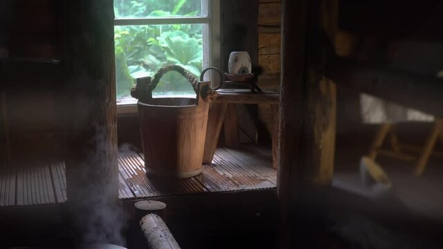Interior of traditional Finnish sauna with wooden accessories and steam. Splashing water on hot stones.