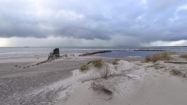 Cloudy sunset at Baltic sea coast near Sventoji village. Stormy clouds and ruins of an old wooden  bridge in a distance. Wide angle panoramic view.