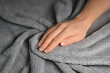 Woman touching grey blanket, close up. Close up of hand touching soft blanket. Gentle and fluffy blanket between fingers. - obrazy, fototapety, plakaty