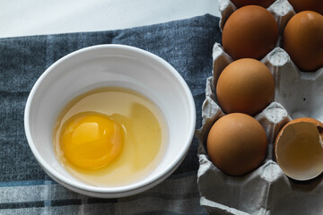 Top view of a plate with a broken egg near a chicken box on a gray napkin on the table.