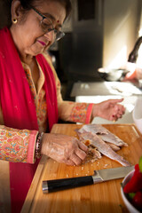 Obraz na płótnie Canvas Indian woman cutting fish in her kitchen 