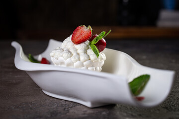 serving meringue dessert with strawberries in a white plate