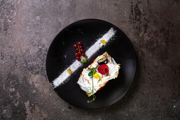 top view biscuit roll with berries on a stylish black plate