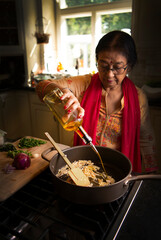 Woman cooking and adding oil to the pan 