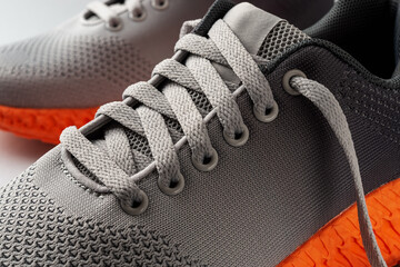 Lacing up the sneakers. Elastic laces of gray mesh fabric sneakers with orange grooved sole. Modern...