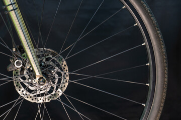A photo of the front bicycle wheel taken in a professional studio with studio light and a black background. High-quality bicycle workshop, mountain bike repair, tire and brake close-up.