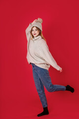 A girl in a hat and a light sweater on a red background